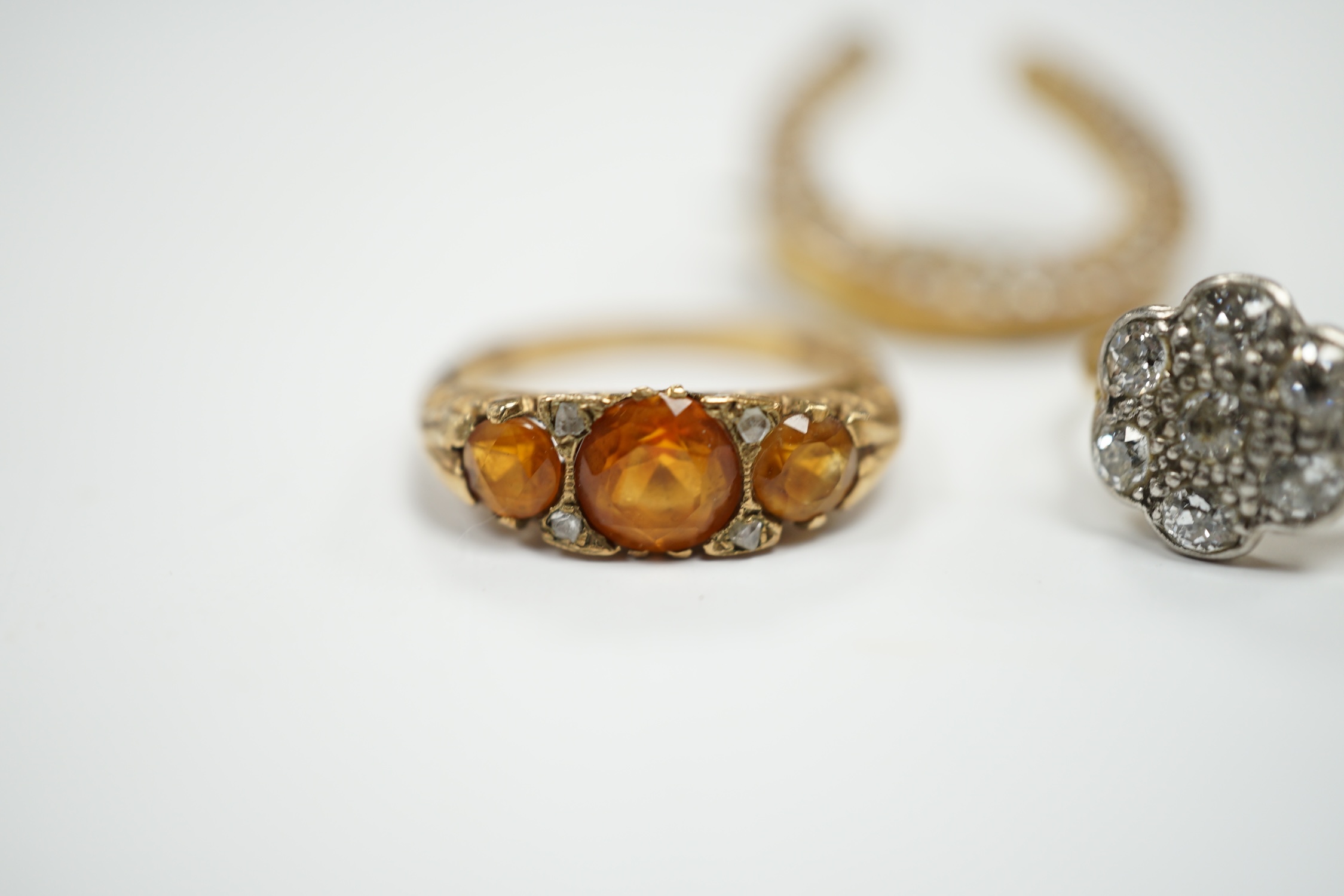 A 1920's 18ct, plat and millegrain set diamond flower head cluster ring, size L/M, a later 9ct gold and three stone citrine ring, with rose cut diamond chip spacers and a yellow metal seed pearl cluster set horseshoe bro